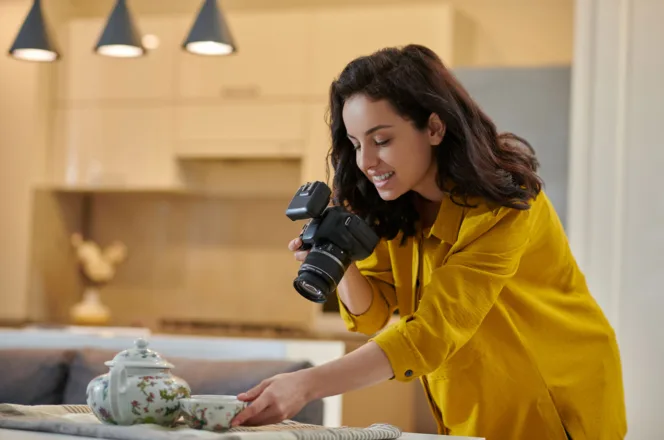 Photographer in a yellow top shooting with a DSLR camera in a home kitchen