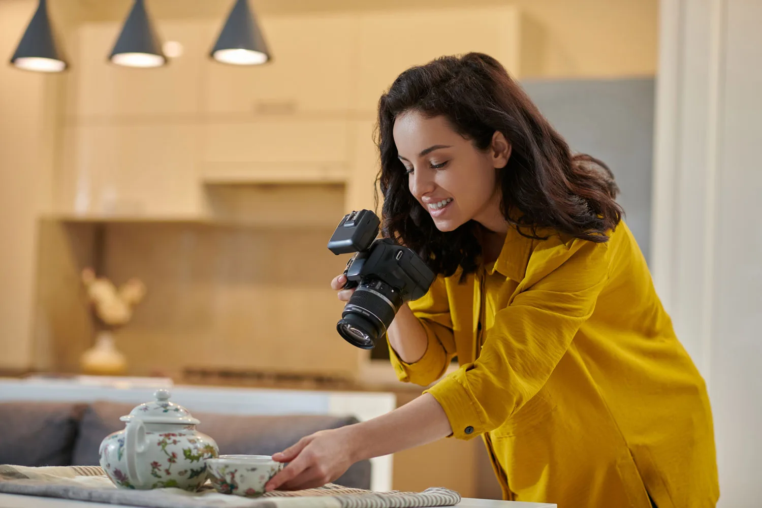 Photographer in a yellow top shooting with a DSLR camera in a home kitchen
