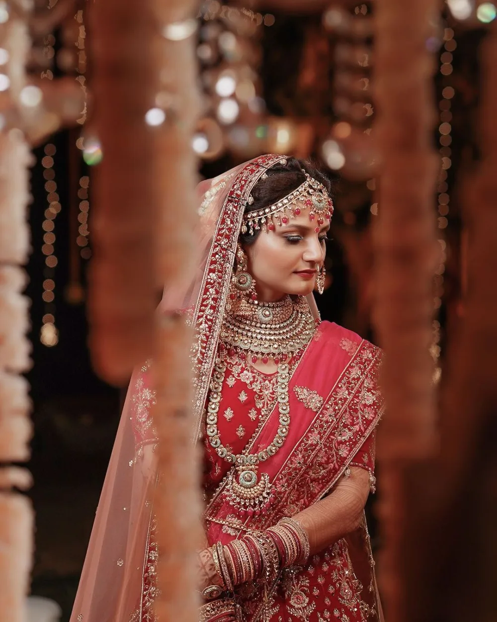 Bride in a red lehenga photographed under decorative lights, wedding photography Bangalore