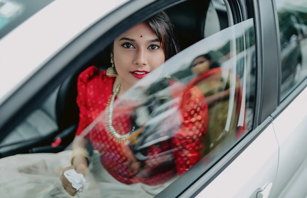 Bride photographed through a car window on arrival, candid wedding photography Bangalore