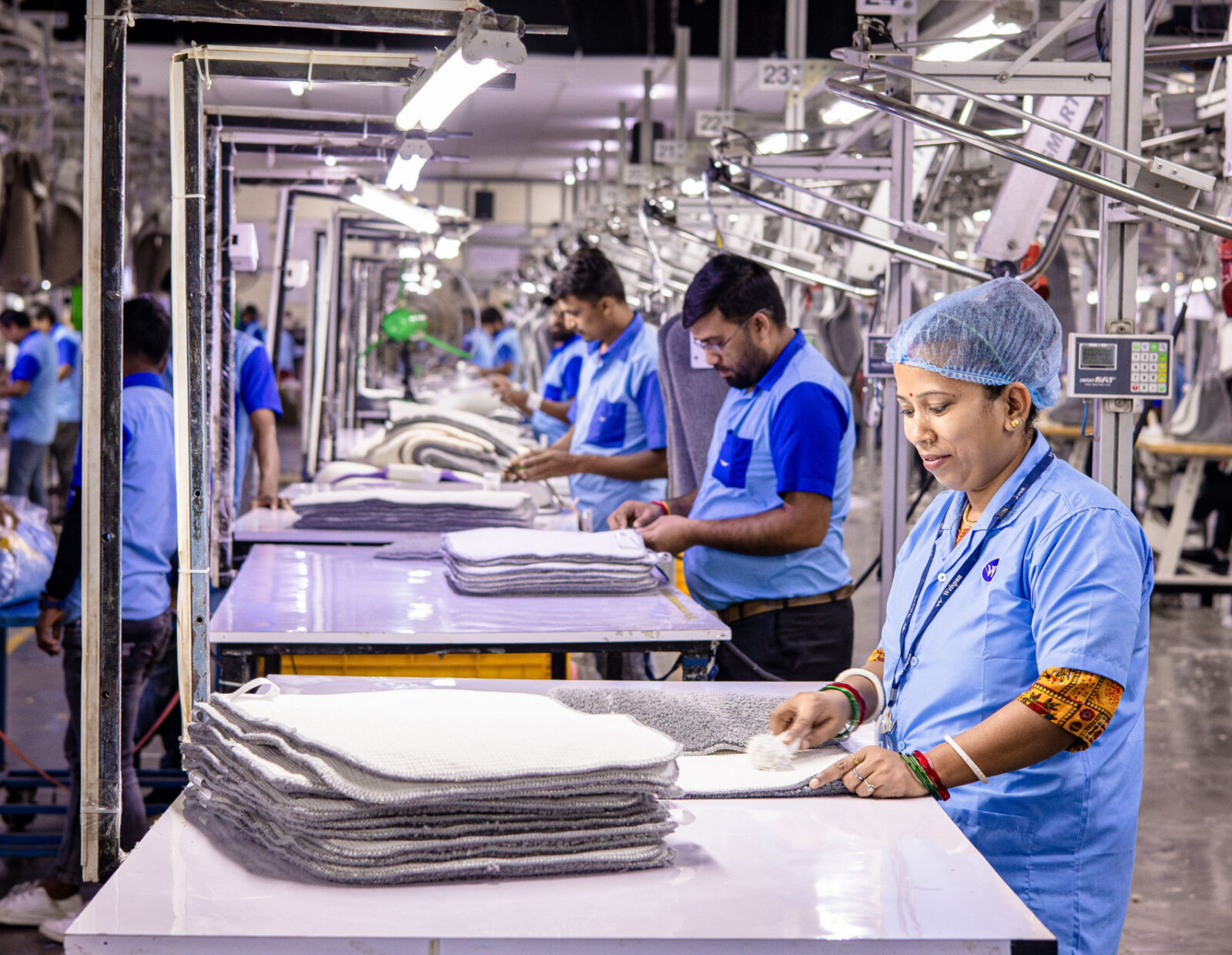 Workers folding fabric along a garment factory production line